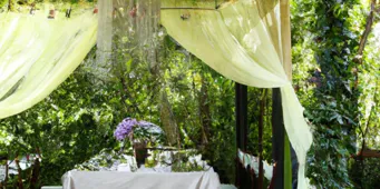 pergola charmante avec rideaux en tissu dans un jardin luxuriant pour un coin repas extérieur
